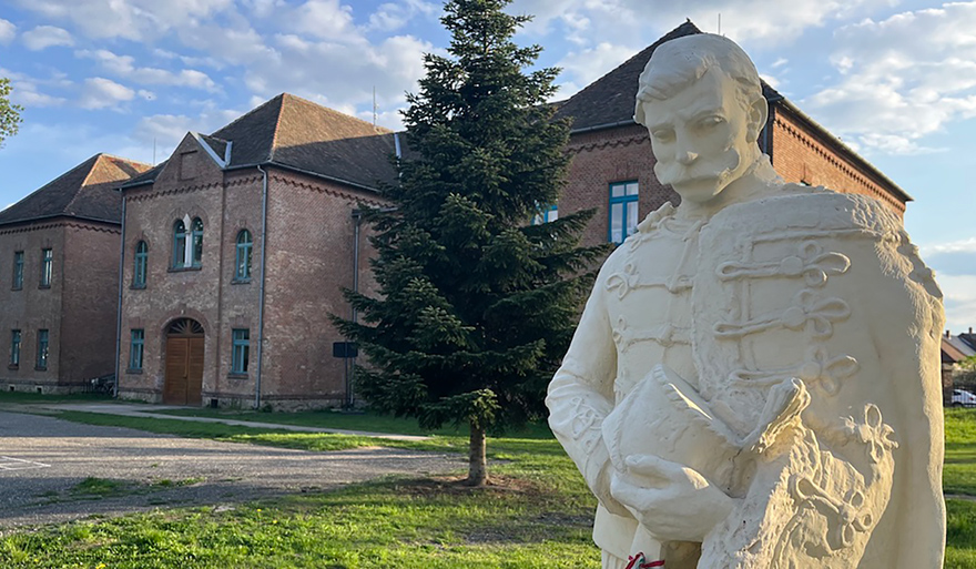 A hussar soldier statue stands in front of a former military building refurbished into a school